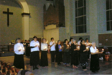 Large group of dancers holding candles